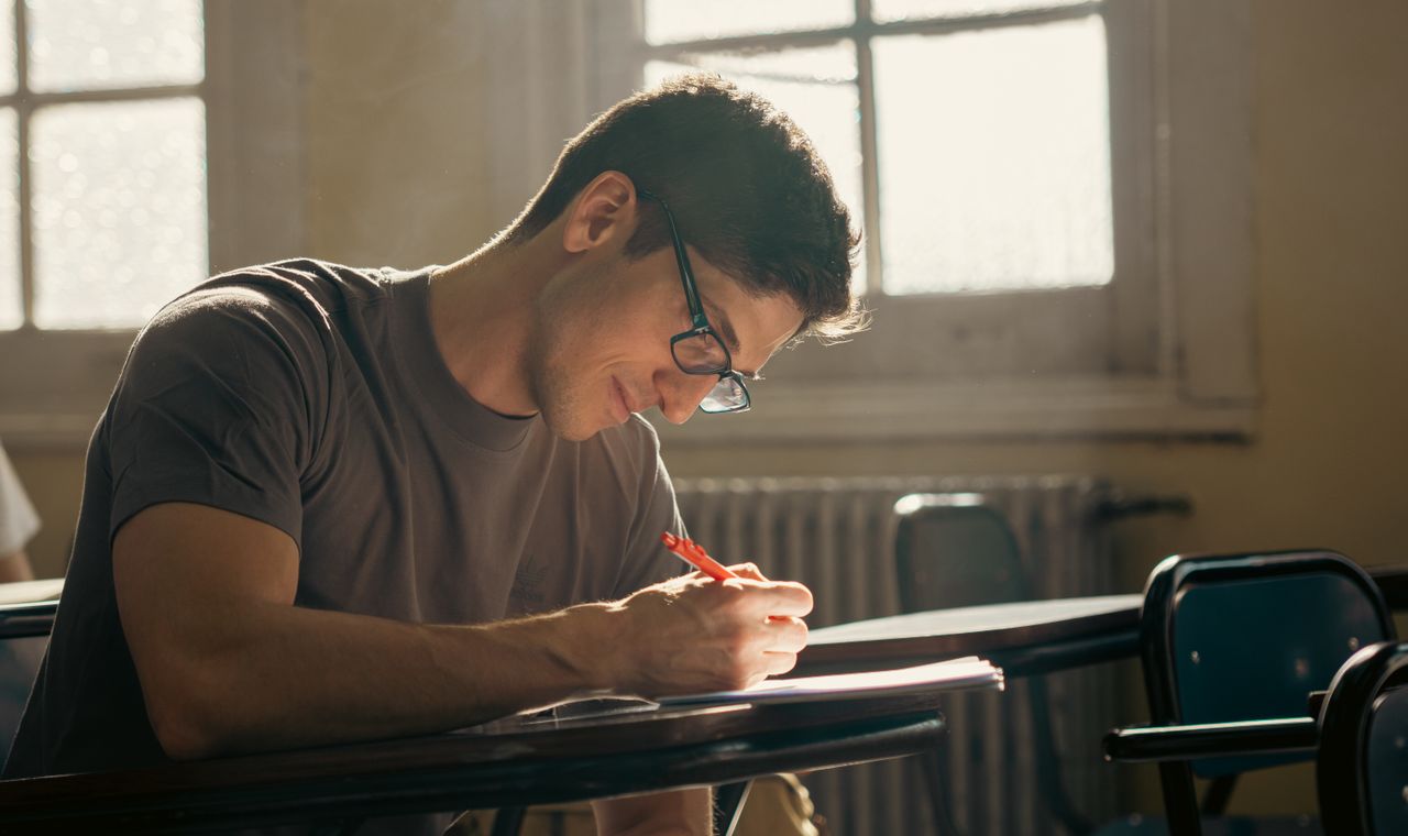 Lycéen concentré écrivant en classe